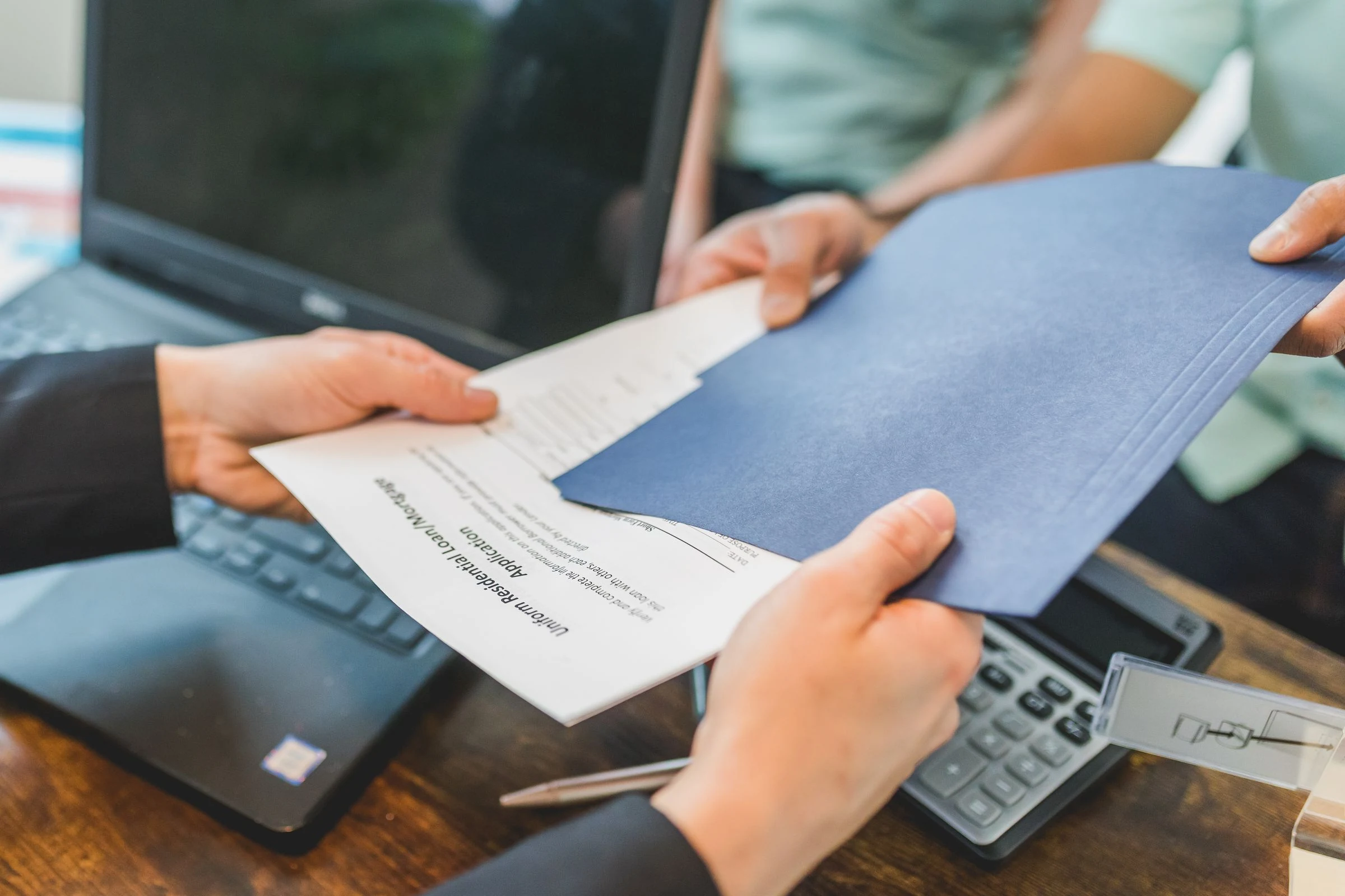 Échange de documents immobiliers entre un conseiller et son client pour préparer une analyse