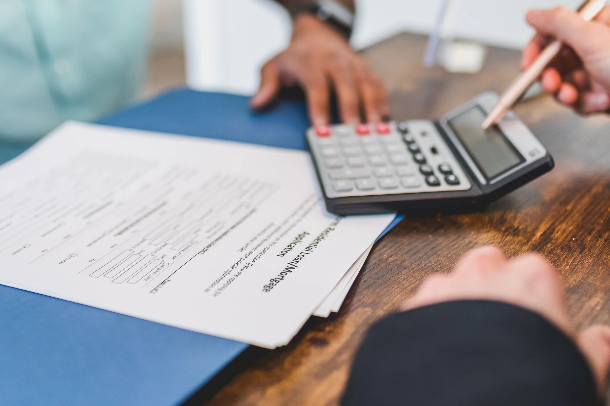 Analyse d’un budget immobilier avec une calculatrice et des documents lors d’un échange professionnel