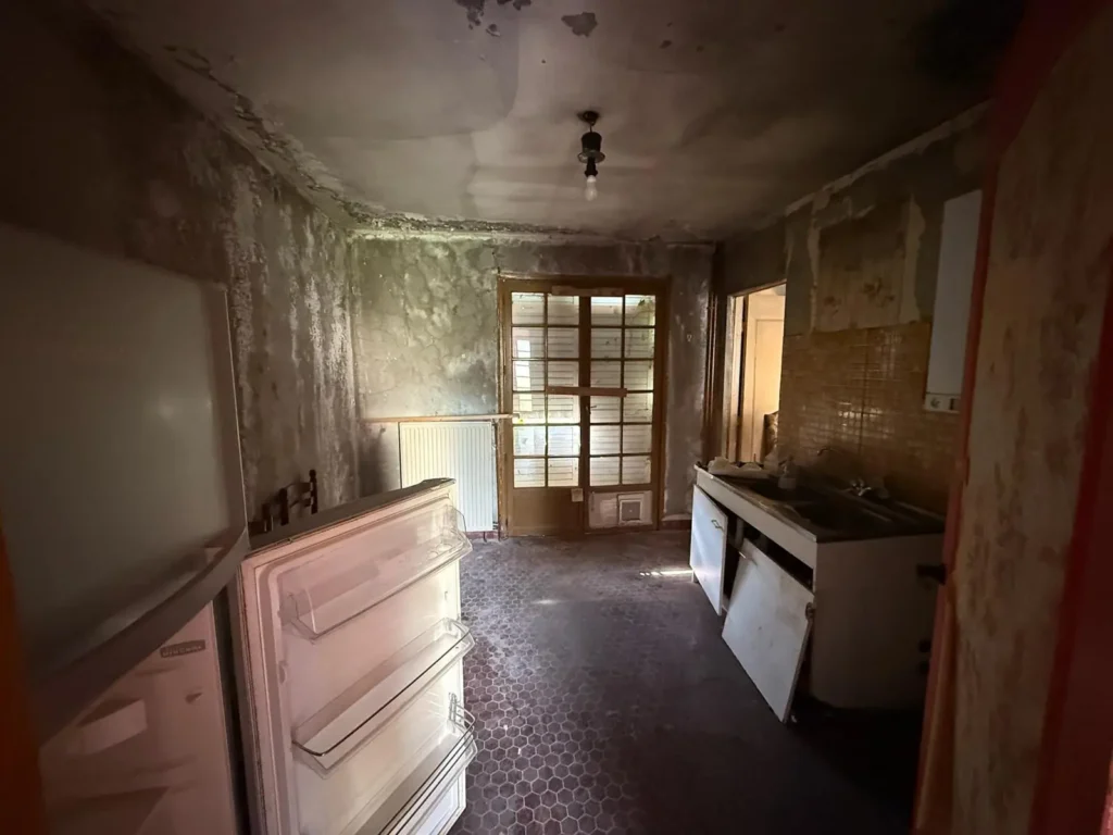 Cuisine d’un pavillon avant rénovation complète : murs dégradés, ancien évier et sol à remplacer