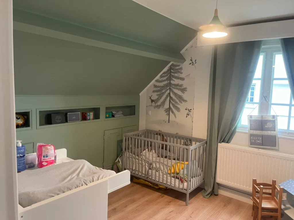 Chambre d’enfant sous combles rénovée en vert sauge avec niches de rangement conservées, rénovation accompagnée par Signature Travaux