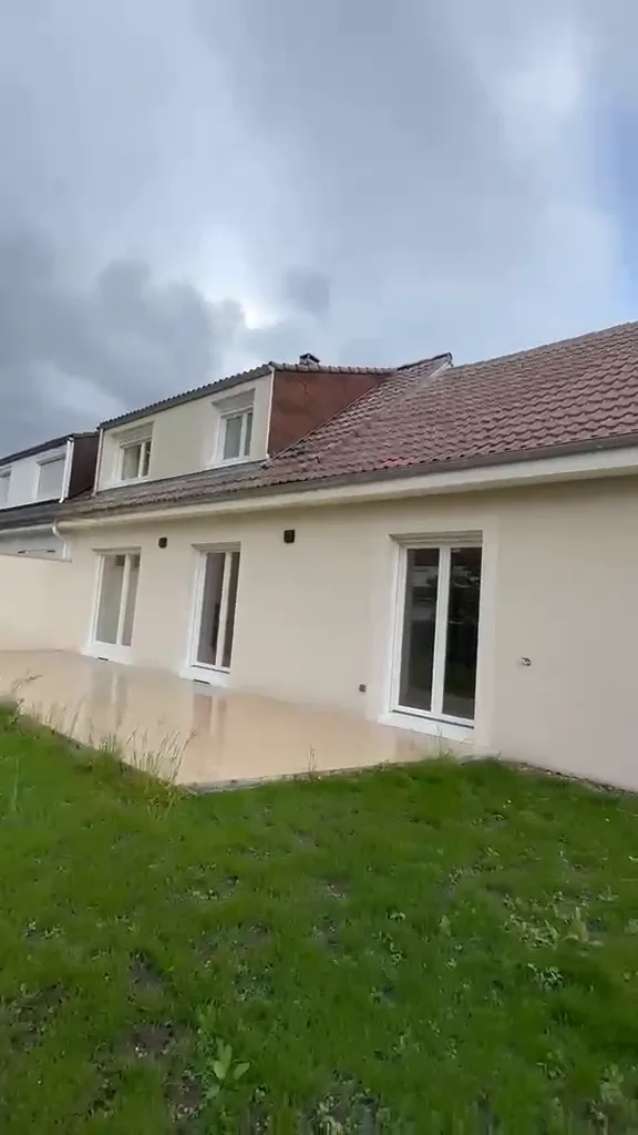 Façade arrière d’un pavillon rénové : enduit clair, fenêtres neuves, terrasse et pelouse