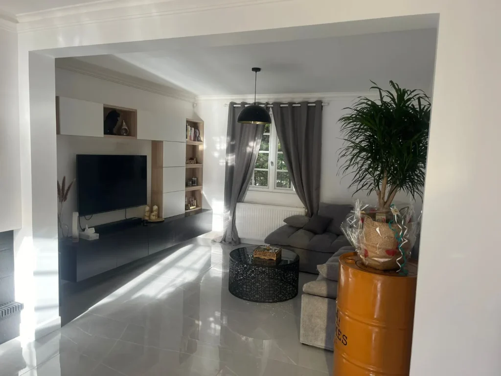 Séjour rénové avec meuble TV sur mesure et carrelage effet marbre après rénovation de maison accompagnée par Signature Travaux